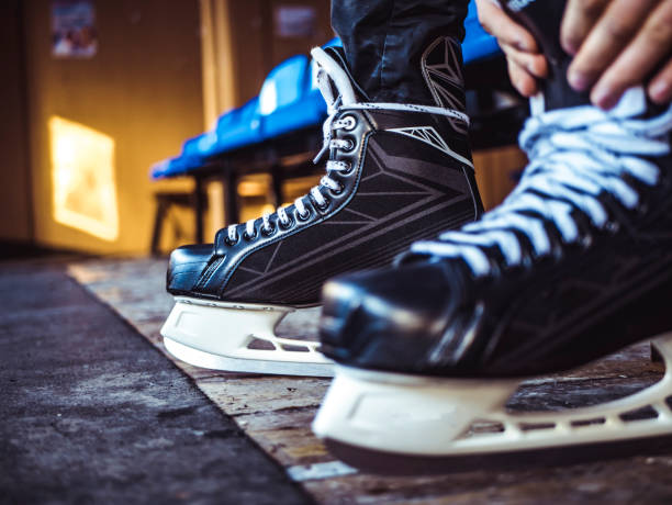 close up shot of hand tie shoelaces of ice hockey skates in locker room